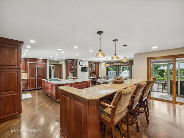 kitchen with glass insert cabinets, a kitchen bar, a spacious island, and dark wood-style floors