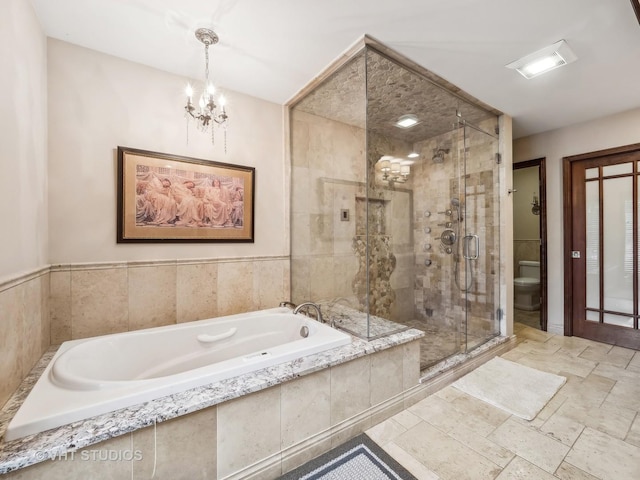 full bathroom featuring a bath, toilet, stone finish floor, a chandelier, and a stall shower