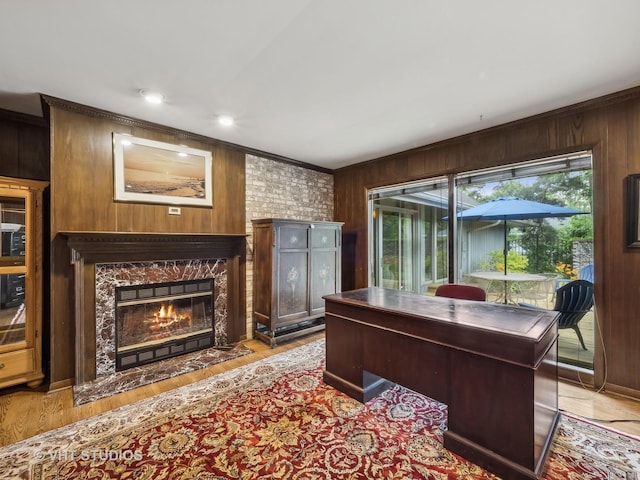 office area with crown molding, wooden walls, a fireplace, and light wood-style floors
