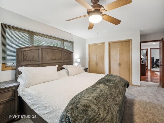 bedroom with ceiling fan, carpet flooring, two closets, and baseboards