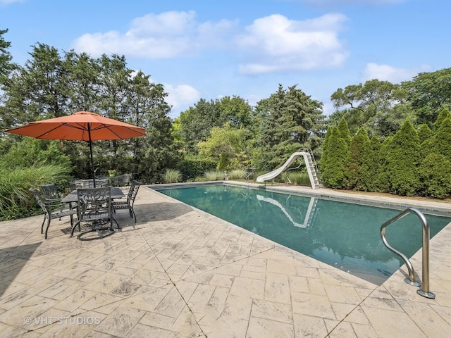pool with outdoor dining space, a patio area, and a water slide