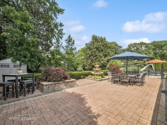 view of patio / terrace featuring an outbuilding, outdoor dining space, and fence