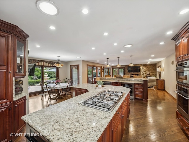 kitchen featuring dark wood-type flooring, wine cooler, recessed lighting, stainless steel appliances, and a large island with sink