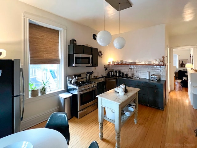 3615 N Janssen Ave, Chicago, IL 60613 - kitchen featuring a sink, decorative backsplash, light wood-type flooring, dark countertops, and appliances with stainless steel finishes