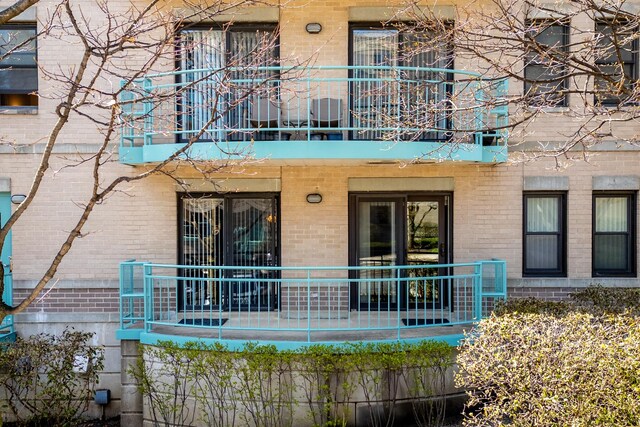back of house with brick siding and a balcony