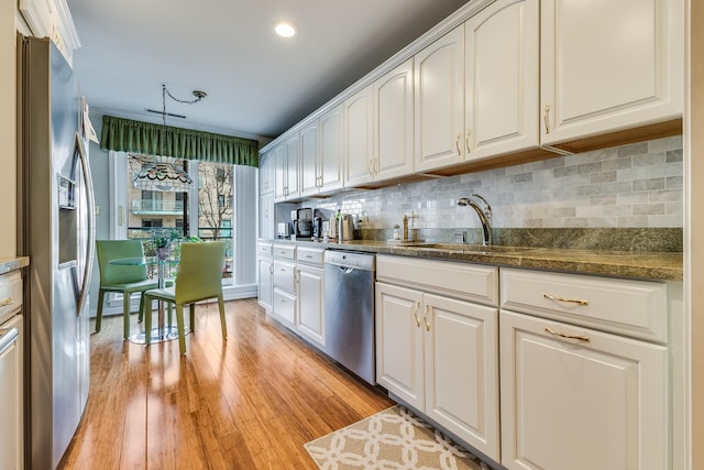 kitchen with light wood-style floors, appliances with stainless steel finishes, decorative backsplash, and white cabinets