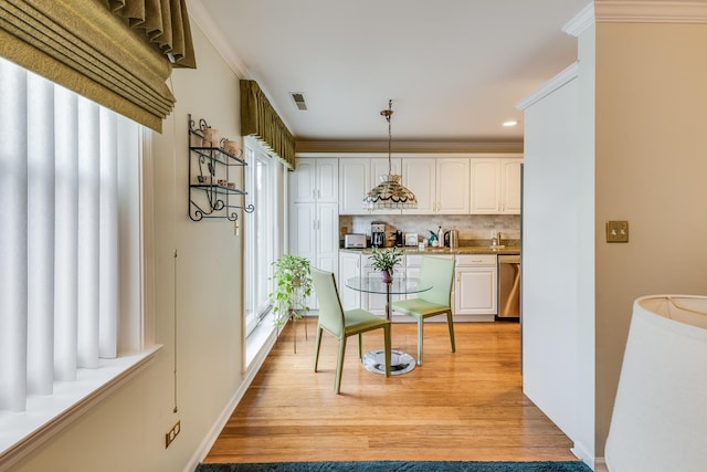 interior space with crown molding, a toaster, visible vents, and light wood-style floors