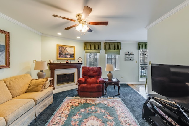 living area featuring crown molding, ceiling fan, a glass covered fireplace, baseboards, and dark wood-style floors