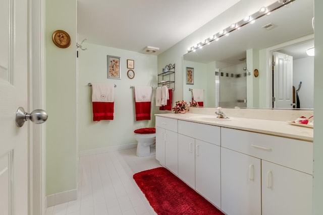 bathroom with a shower stall, vanity, visible vents, toilet, and baseboards