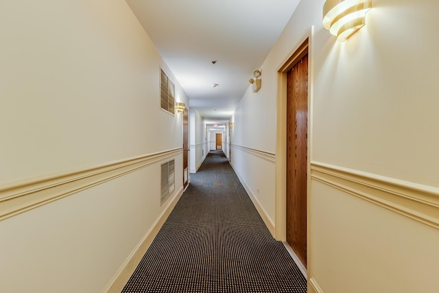 corridor featuring visible vents, wainscoting, and carpet floors