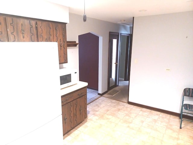 kitchen with light countertops, white appliances, baseboards, and light floors