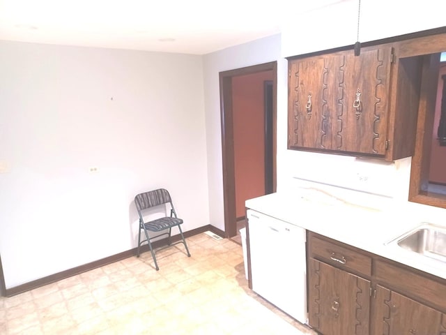 kitchen featuring baseboards, light countertops, light floors, dishwasher, and a sink