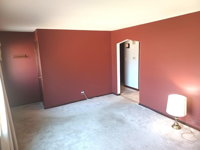 spare room with arched walkways and light colored carpet
