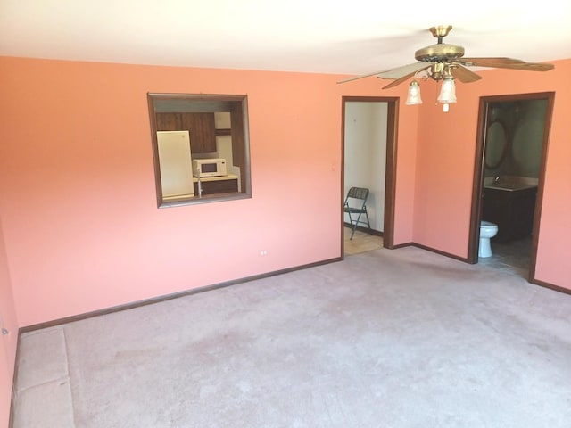 carpeted spare room with baseboards and a ceiling fan