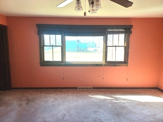 carpeted empty room featuring visible vents and ceiling fan