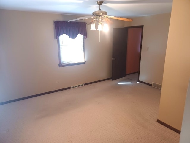 empty room with light carpet, visible vents, baseboards, and a ceiling fan