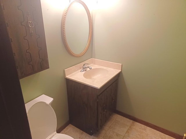 half bathroom with toilet, tile patterned floors, vanity, and baseboards