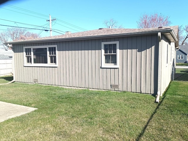 view of property exterior featuring board and batten siding, fence, and a lawn