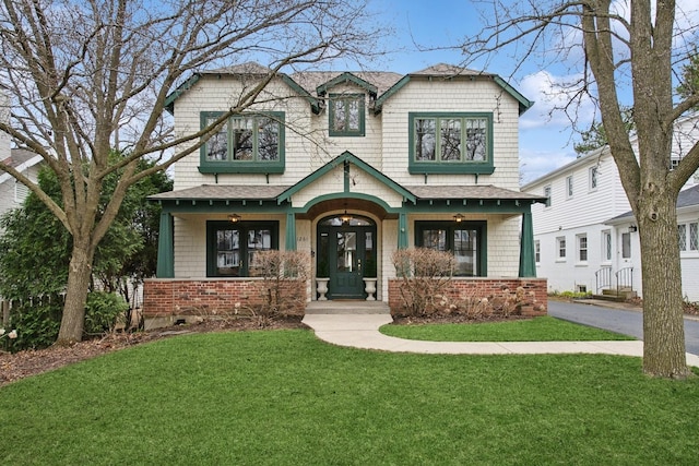 craftsman inspired home featuring a front yard, roof with shingles, and a porch