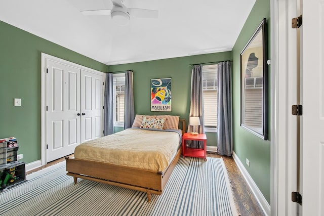 bedroom with a closet, baseboards, a ceiling fan, and wood finished floors