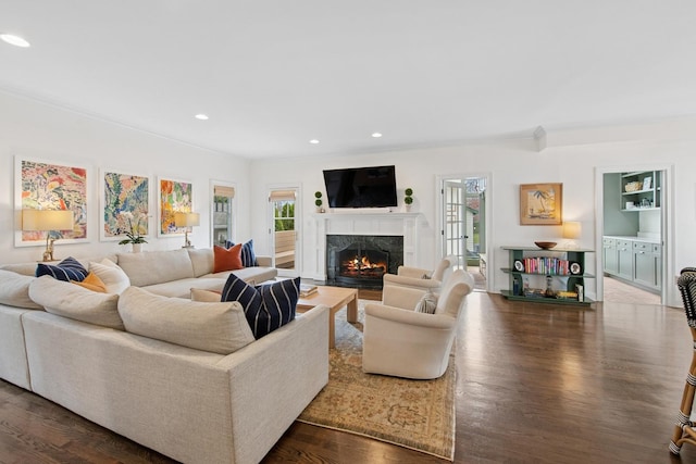 living area with recessed lighting, a high end fireplace, dark wood-style flooring, and crown molding
