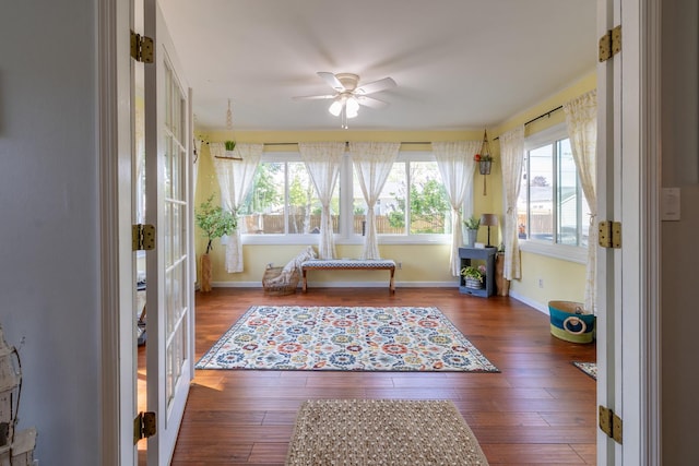 sunroom featuring wood finished floors, baseboards, and french doors