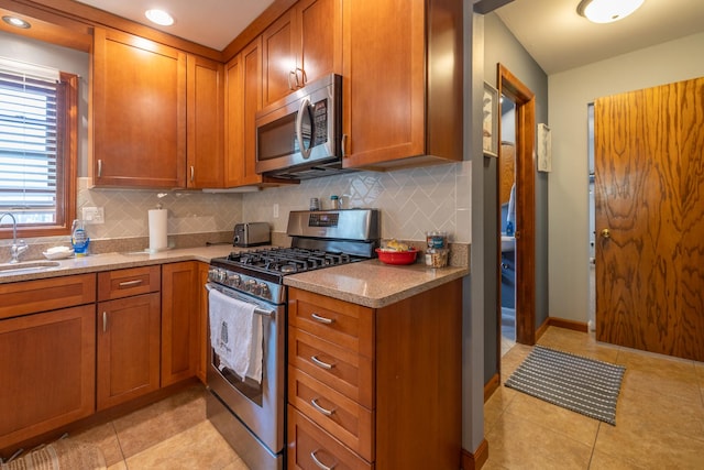 kitchen with appliances with stainless steel finishes, a sink, brown cabinetry, and decorative backsplash