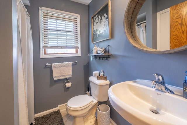 bathroom with a sink, toilet, baseboards, and tile patterned floors