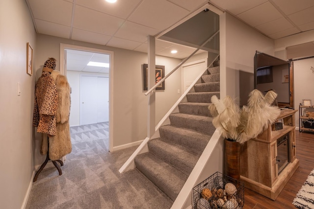 stairs featuring a paneled ceiling, baseboards, wood finished floors, and recessed lighting