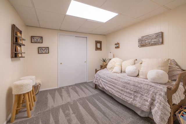carpeted bedroom featuring a drop ceiling and a closet