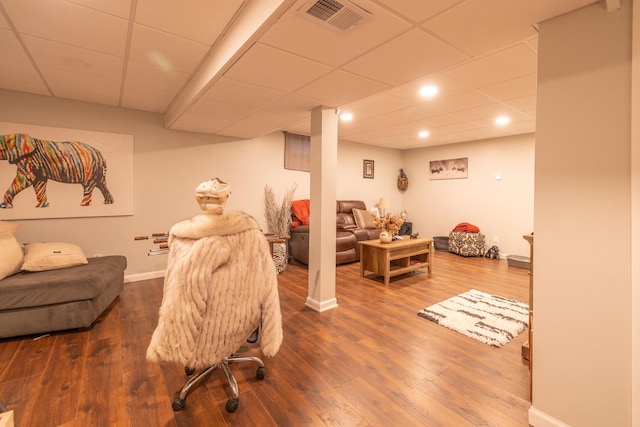 living room featuring a drop ceiling, recessed lighting, baseboards, and wood finished floors