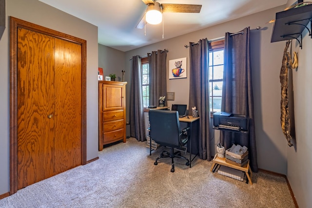 carpeted office space with a ceiling fan and baseboards