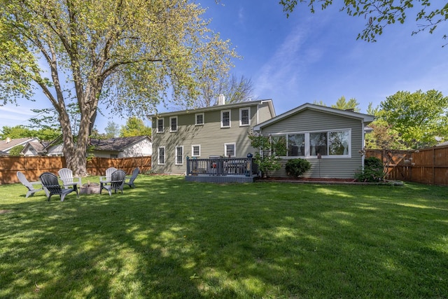 back of house featuring a fire pit, a chimney, and a deck