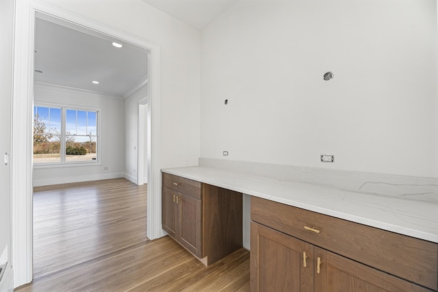 kitchen with baseboards, light wood-type flooring, ornamental molding, light stone counters, and recessed lighting