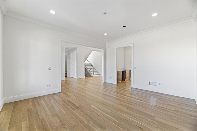 empty room with light wood-style flooring, baseboards, ornamental molding, and stairs