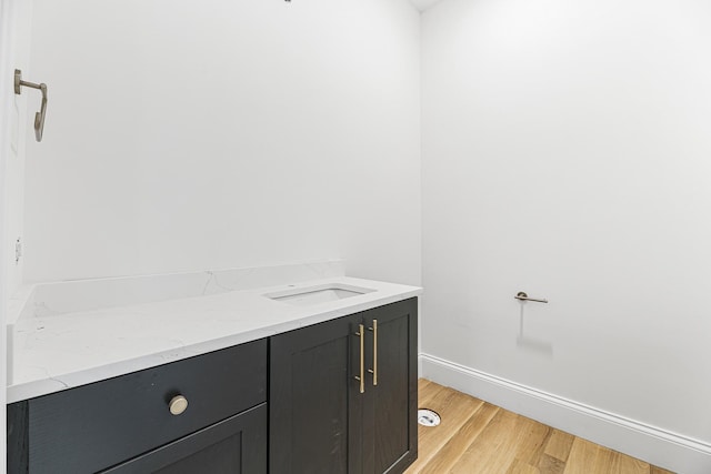 bathroom featuring wood finished floors, a sink, and baseboards