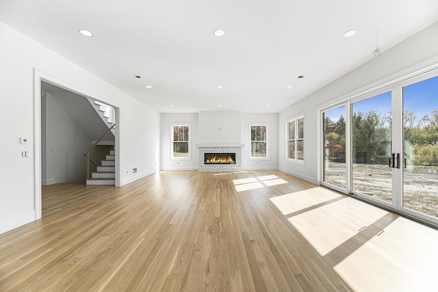 unfurnished living room featuring recessed lighting, stairway, light wood-type flooring, and baseboards