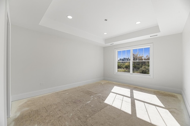 empty room with a tray ceiling, baseboards, and recessed lighting