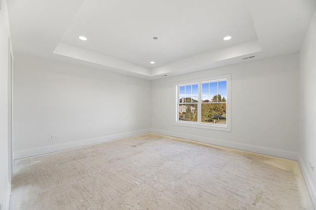 empty room with visible vents, baseboards, and a raised ceiling