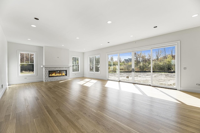 unfurnished living room featuring wood finished floors, baseboards, a glass covered fireplace, and recessed lighting