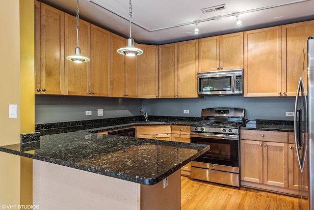 kitchen featuring a peninsula, decorative light fixtures, visible vents, dark stone counters, and stainless steel appliances