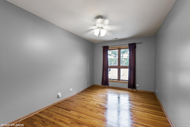 empty room featuring light wood finished floors, visible vents, baseboards, and ceiling fan
