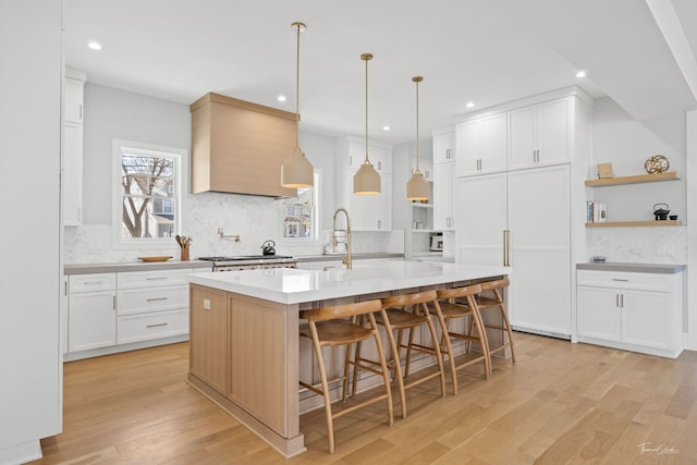 kitchen featuring decorative backsplash, open shelves, recessed lighting, a large island with sink, and light wood-style flooring