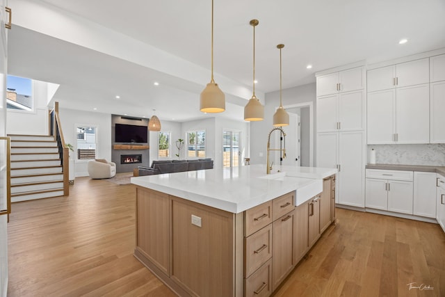 kitchen featuring recessed lighting, a lit fireplace, a sink, and light wood-type flooring