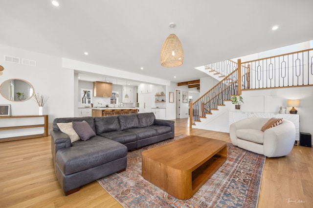 living area featuring recessed lighting, light wood-type flooring, stairs, and visible vents