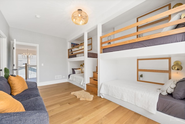 bedroom with visible vents, wood finished floors, baseboards, a notable chandelier, and access to outside
