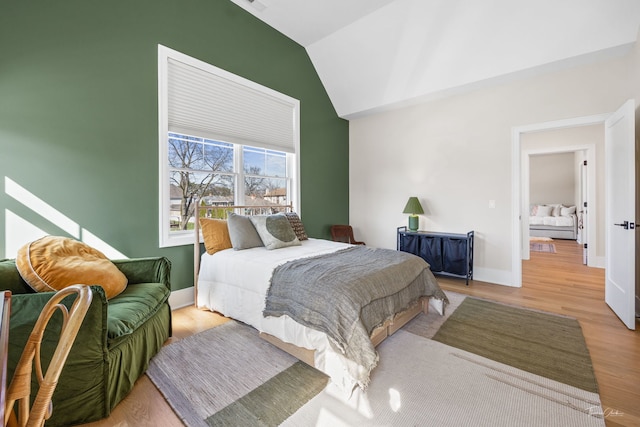 bedroom featuring baseboards, vaulted ceiling, and wood finished floors