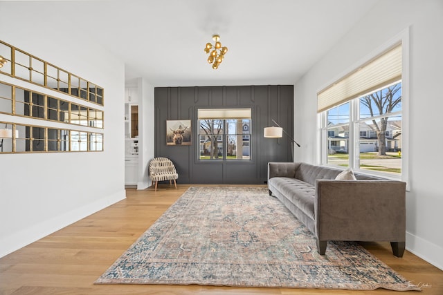 living area with baseboards, wood finished floors, and an inviting chandelier