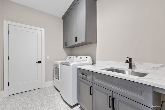 laundry area featuring separate washer and dryer, a sink, cabinet space, and baseboards
