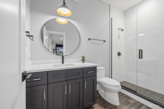 full bathroom with vanity, toilet, a marble finish shower, and wood finished floors
